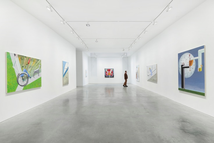 figure in a long gallery with several paintings